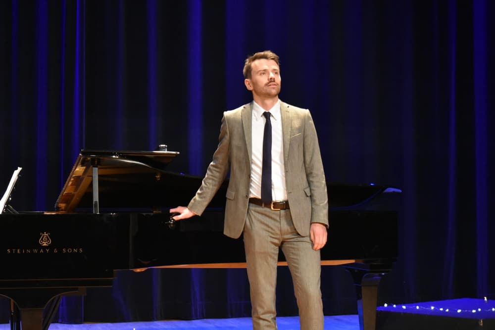 Julien Capy, baryton-basse, sur scène en récital près d'un piano à queue